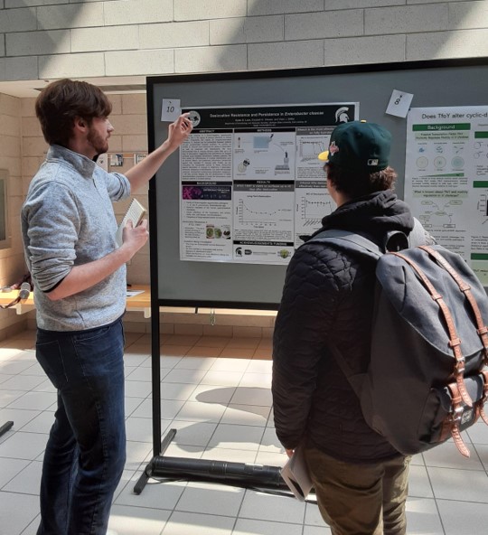 Dylan explaining his research to a showcase attendee